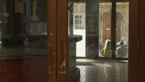 Wide-Shot-Looking-Through-Window-Panes-at-Pedestrians-Sitting-On-Street