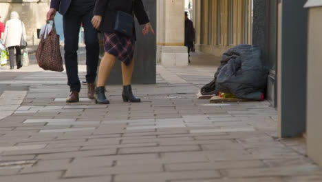 Plano-General-De-Peatones-Pasando-Por-Las-Pertenencias-De-Las-Personas-Sin-Hogar-En-La-Calle