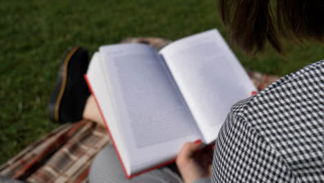 Deslizándose-Sobre-El-Hombro-Shot-De-Mujer-Joven-Libro-De-Lectura-En-El-Parque