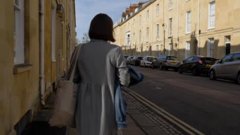 Tracking-Shot-of-Young-Woman-Walking-Around-Quiet-Street-Corner