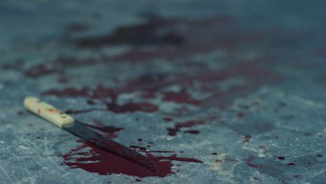 Sliding-Close-Up-Shot-of-Bloody-Knife-On-Floor-of-Disused-Warehouse