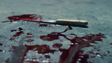Sliding-Close-Up-Shot-of-Bloody-Knife-Scene-On-Floor-of-Disused-Warehouse