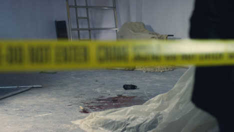 Sliding-Wide-Shot-of-Crime-Scene-In-Warehouse-with-Crime-Scene-Tape-Being-Pulled-In-Foreground