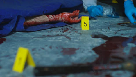 Sliding-Close-Up-Shot-of-a-Bloody-Hand-Underneath-Tarpaulin-at-Crime-Scene