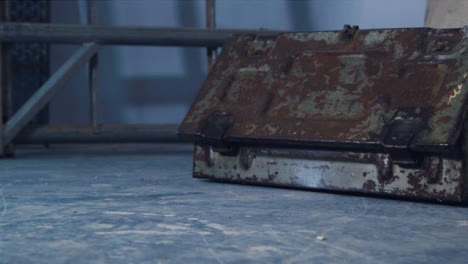 Sliding-Shot-of-Rusted-Old-Tool-Box-and-Paint-Covered-Sheet-In-Disused-Warehouse
