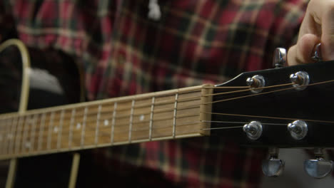 Tracking-Shot-Down-Fret-Board-of-Acoustic-Guitar-as-Musician-Tunes-Strings