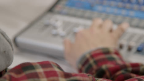 Over-the-Shoulder-Shot-of-Sound-Mixer-Adjusting-Faders