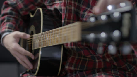 Plano-Medio-Del-Guitarrista-De-Cuerdas-De-Afinación-En-La-Guitarra-Acústica