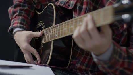 Medium-Shot-of-Musician-Placing-Down-Pen-After-Writing-and-Playing-Acoustic-Guitar