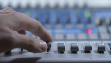 Primer-Plano-De-Mezcladores-De-Audio-Mano-Ajustando-Los-Faders-En-La-Mesa-De-Mezclas-De-Audio