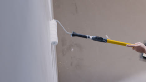 High-Angle-Shot-of-Paint-Roller-Applying-Paint-to-White-Wall