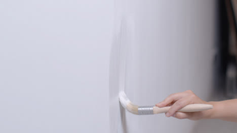 Medium-Shot-of-Person-Painting-White-Wall-with-Paint-Brush