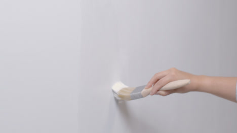 Medium-Shot-of-a-Person-Painting-White-Wall-with-Paint-Brush