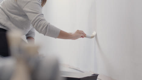 Pull-Focus-Shot-of-a-Person-Painting-White-Wall-with-Paint-Brush