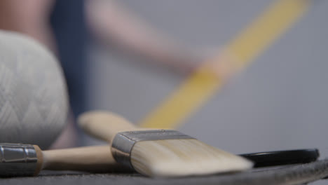 Close-Up-Shot-of-Paint-Brush-as-Person-Paints-In-Background