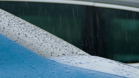 Panning-Shot-of-Heavy-Rain-Falling-On-Blue-Car-Window-and-Body