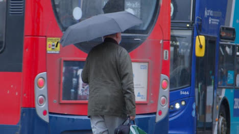 Long-Shot-of-Senior-Man-with-Umbrella-In-Rain