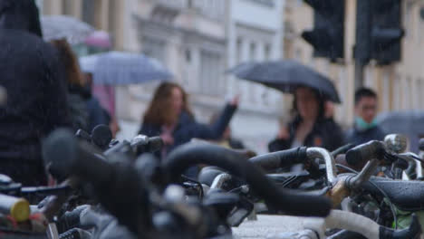 Pedestal-Shot-Past-Bicycle-Rack-Revealing-Rain-Falling-On-Pedestrians-