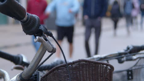 Sliding-Close-Up-Shot-of-Bicycle-Handle-as-Pedestrians-Walk-Past
