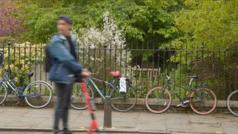 Plano-General-De-Persona-En-Scooter-Eléctrico-Pasando-Por-Delante-De-Bicicletas