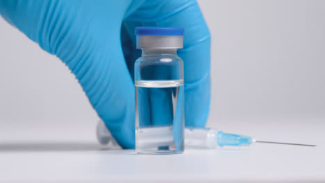 Tracking-Shot-Approaching-Vial-of-Translucent-Liquid-and-Syringe-Before-Hand-Takes-It-Away