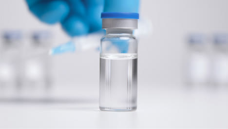 Close-Up-Shot-of-Vial-of-Translucent-Liquid-and-Syringe-Before-Hand-Takes-It-Away