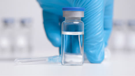 Sliding-Shot-of-Vial-of-Translucent-Liquid-and-Syringe-Before-Hand-Takes-It-Away