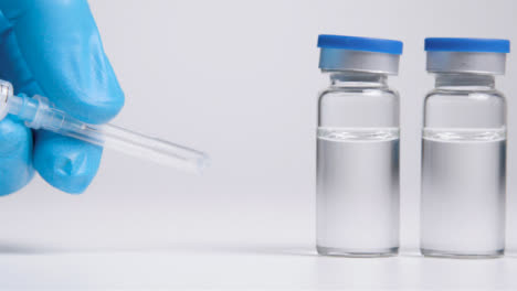 Sliding-Shot-Along-Line-of-Vials-of-Translucent-Liquid-and-Syringe-Before-Hand-Takes-It-Away