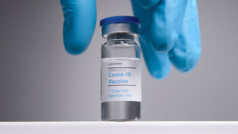 Low-Angle-Tracking-Shot-Approaching-Covid-19-Vaccine-Vial-Before-Hand-Takes-It-Away