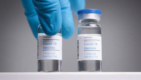 Low-Angle-Tracking-Shot-Approaching-Covid-19-Vaccine-Vials-Before-Hand-Takes-One-Away-
