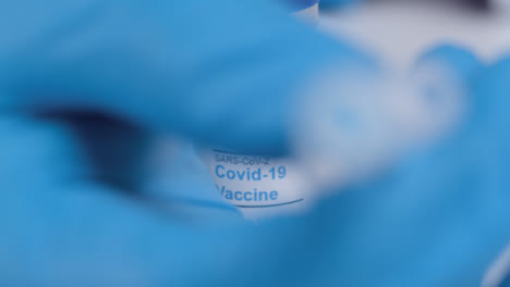 Pull-Focus-Shot-from-Tip-of-Syringe-Needle-to-Covid-19-Vaccine-Vial-Label