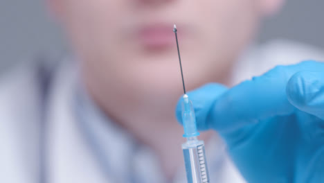 Close-Up-Shot-of-Medical-Professional-Removing-Excess-Solution-from-Syringe-Needle-Tip