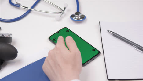 Disparo-Por-Encima-Del-Hombro-De-Un-Profesional-Médico-Con-Pantalla-Táctil-De-Smartphone-Con-Pantalla-Verde