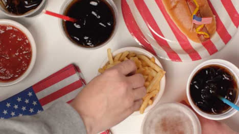 Top-Down-Shot-of-Hands-Taking-Fries-and-Beer-from-Party-Food-Spread