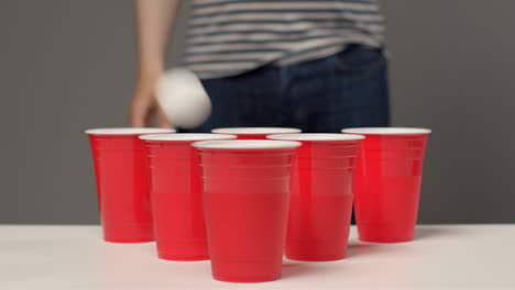 Tiro-Deslizante-Acercándose-A-Vasos-De-Plástico-Como-Persona-En-El-Fondo-Juega-Beer-Pong