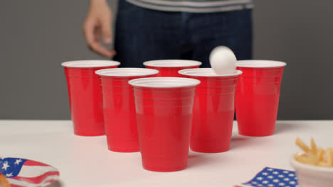 Schiebeschuss-Nähert-Sich-Tassen-Als-Person-Im-Hintergrund-Trinkt-Während-Des-Beer-Pong-Spiels