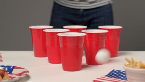 Tiro-Deslizante-Acercándose-A-Vasos-De-Plástico-Como-Una-Persona-En-El-Fondo-Juega-Beer-Pong