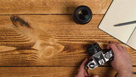 Top-Down-Shot-of-Person-Picking-Up-an-SLR-Camera-from-Table-with-Left-Copy-Space