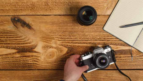 Top-Down-Shot-of-Person-Picking-Up-SLR-Camera-from-Table-with-Left-Copy-Space