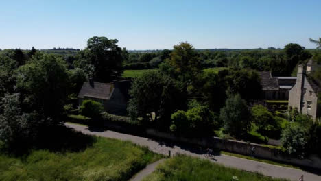 Drone-Shot-Flying-Low-Over-Field-Before-Rising-Up-Over-Rural-Manor-Houses