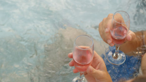 High-Angle-Shot-Looking-Down-On-People-Holding-Champagne-Glasses-In-Hot-Tub