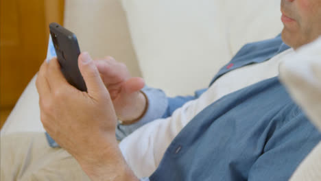 High-Angle-Shot-of-Middle-Aged-Man-Scrolling-On-His-Smartphone