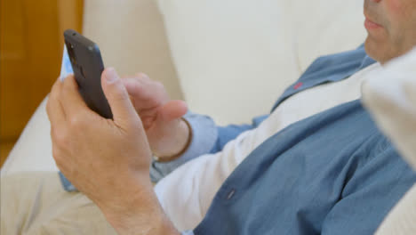 Disparo-De-Alto-ángulo-De-Hombre-De-Mediana-Edad-Desplazándose-En-Su-Smartphone