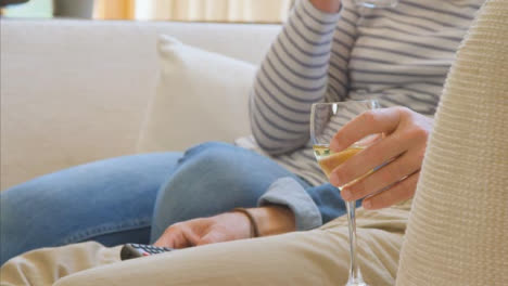 Close-Up-Shot-of-a-Middle-Aged-Couples-Hands-as-They-Sit-On-Sofa-Watching-TV-with-Wine