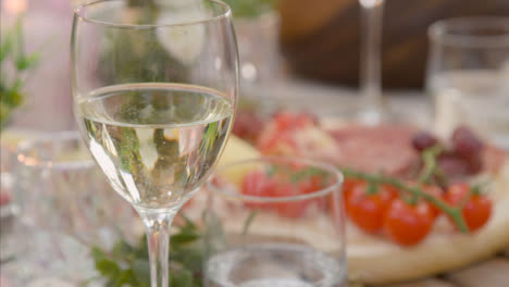 Pull-Focus-Shot-from-Alfresco-Dinner-Table-Spread-to-Glass-of-White-Wine