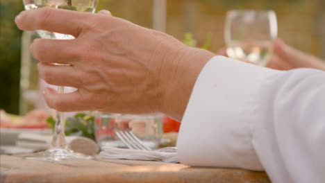 Ziehen-Sie-Den-Fokus-Von-Einem-Abendessen-Im-Freien-Auf-Ein-Glas-Weißwein,-Das-Auf-Dem-Tisch-Steht