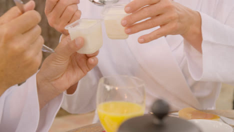 Medium-Shot-of-Middle-Aged-Couple-Playfully-Bringing-Yoghurt-Pots-Together