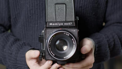 Tracking-Shot-Approaching-Persons-Hands-Holding-Mamiya-RB67-and-Taking-Photo