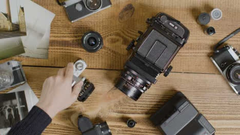 Top-Down-Shot-of-a-Persons-Hands-Placing-Vintage-Film-Camera-On-Table