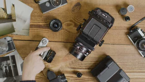 Top-Down-Shot-of-Photographers-Hand-Deciding-What-Vintage-Camera-to-Use